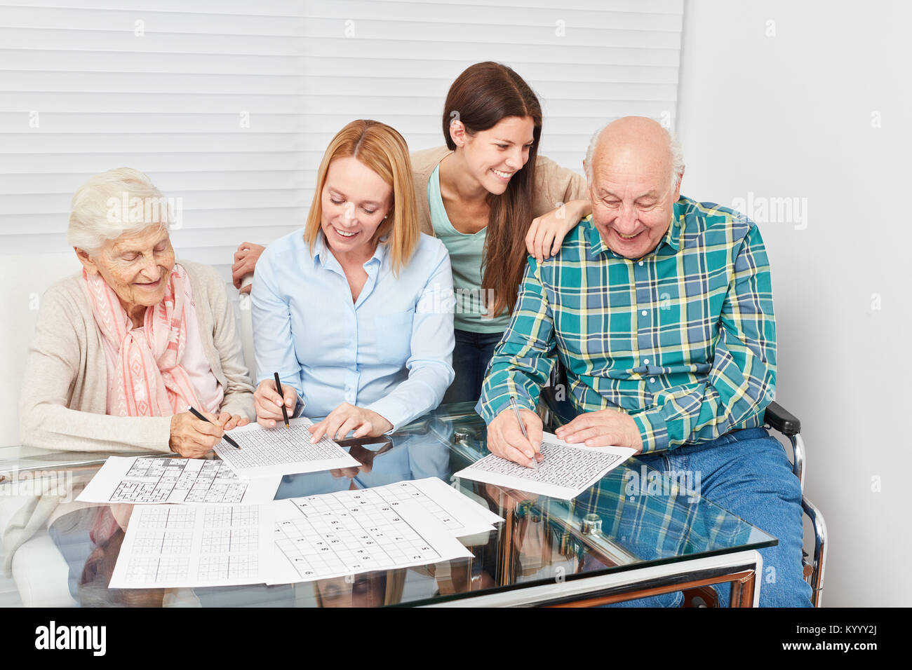 Family with seniors solve puzzles as memory training against dementia Stock Photo