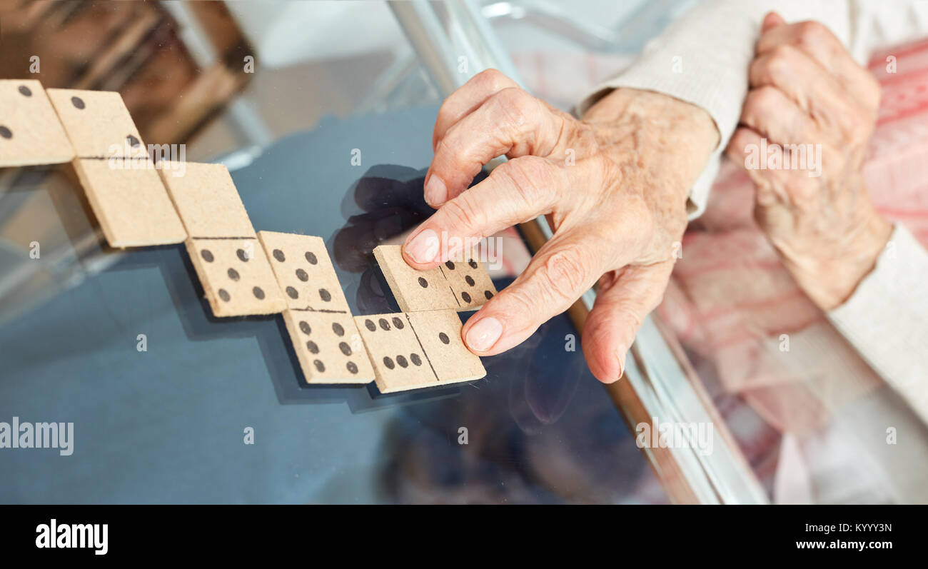 Old hands of seniors lay playing pieces while playing dominoes in retirement home Stock Photo