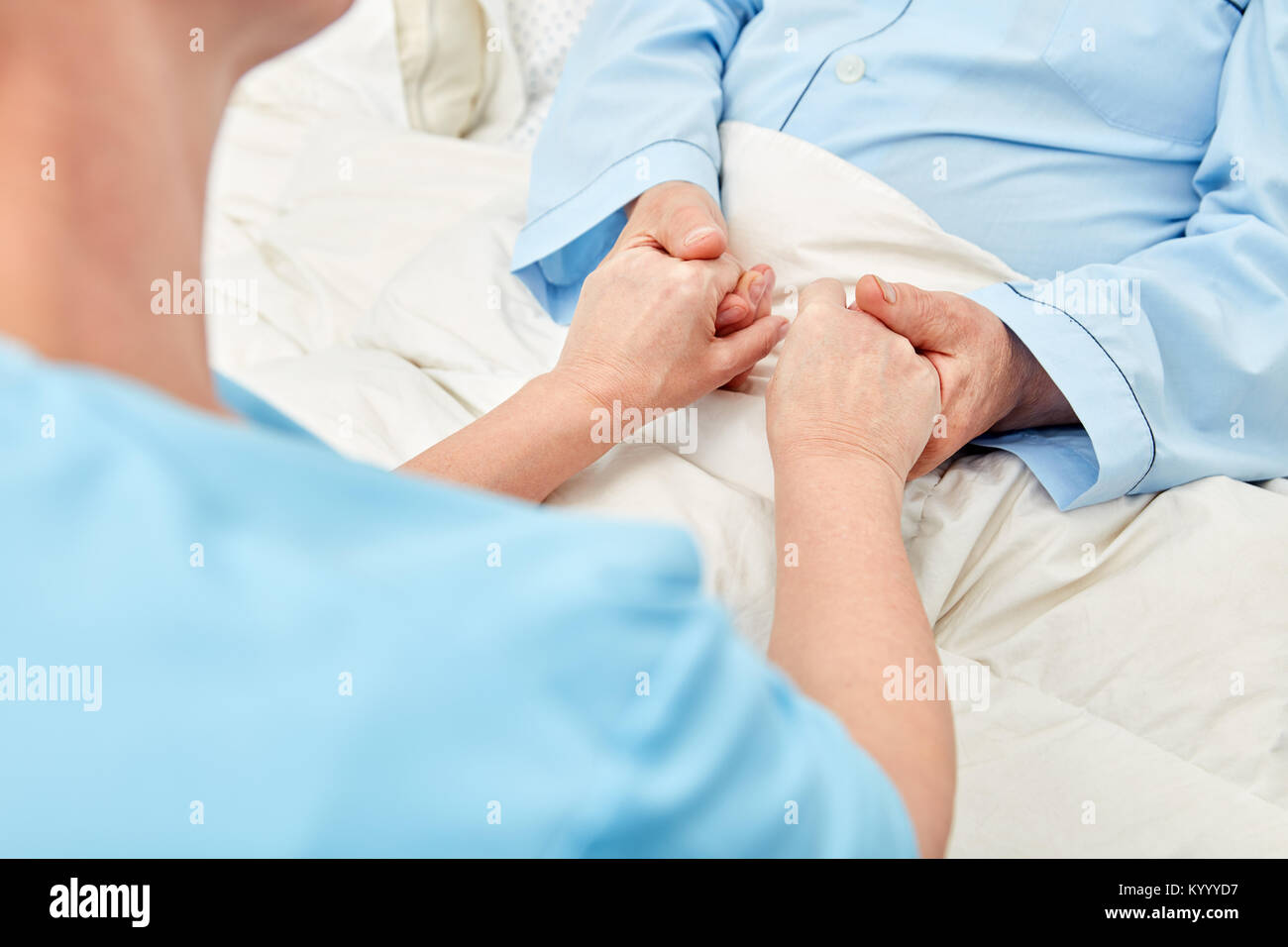 Woman holds the hands of a senior citizen in the hospice and gives consolation as a terminal care Stock Photo