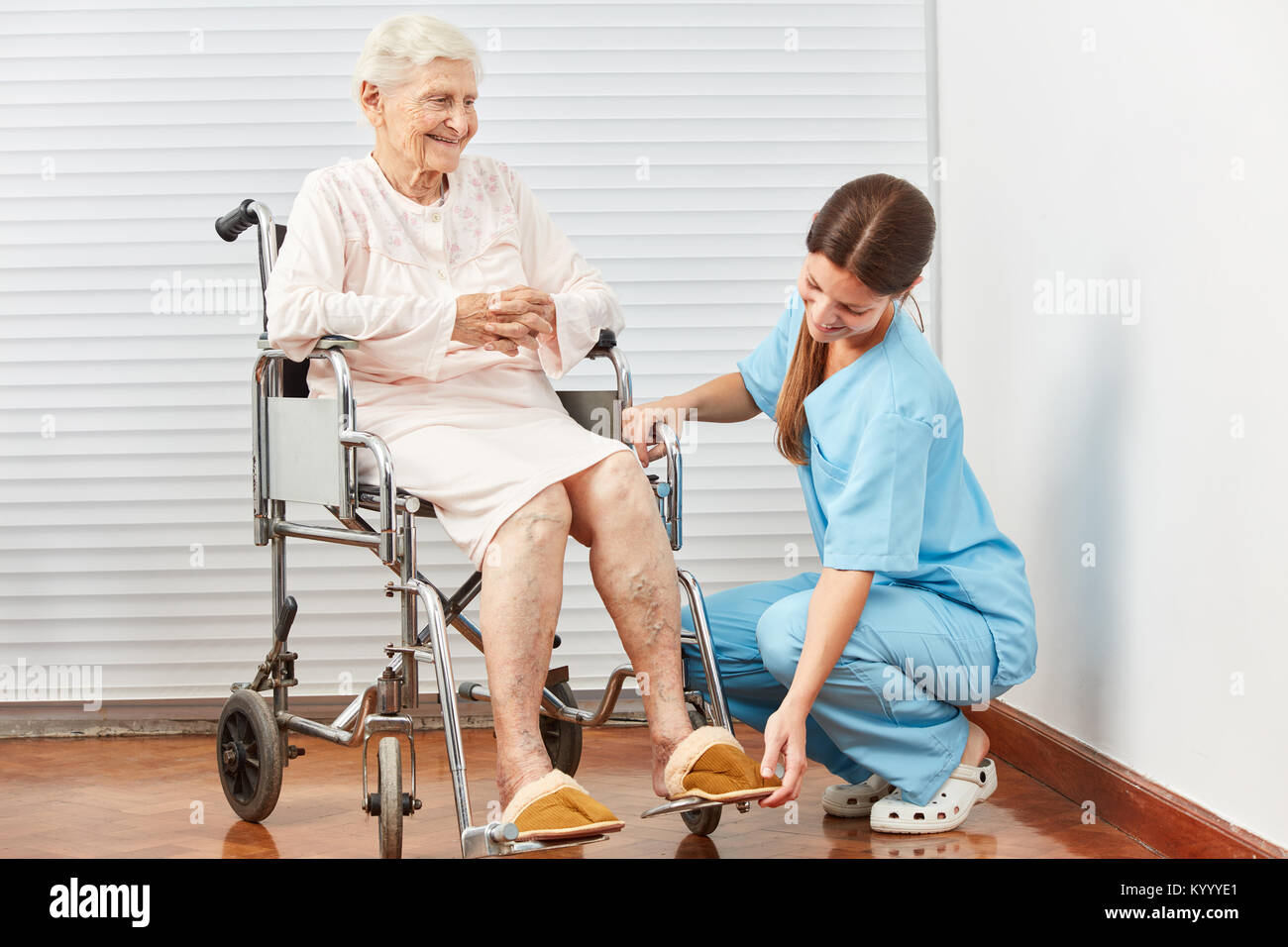 Caregiver helps disabled woman in wheelchair at home or in retirement
