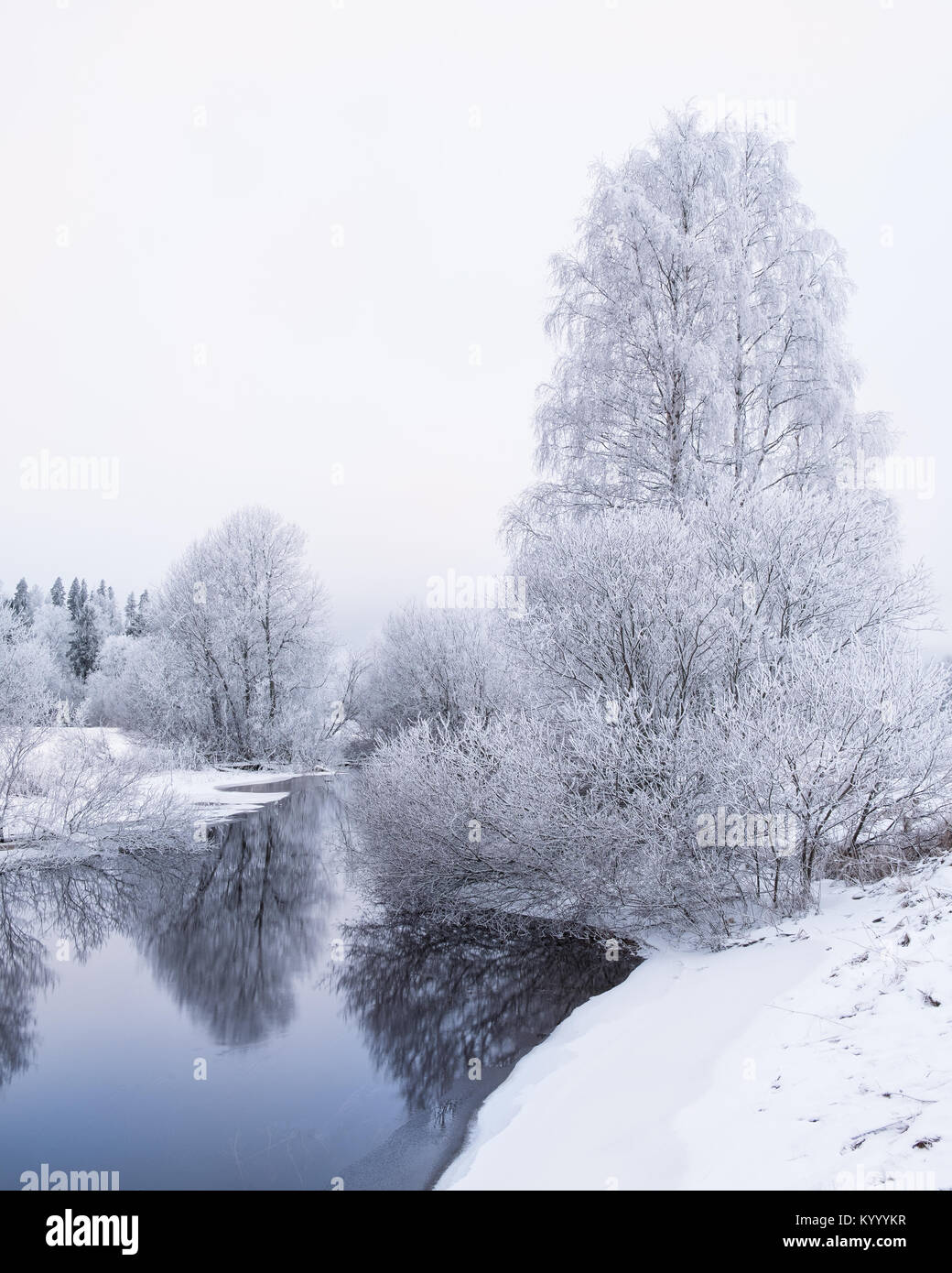 Winter landscape with frosty trees and peaceful river at evening in Finland Stock Photo