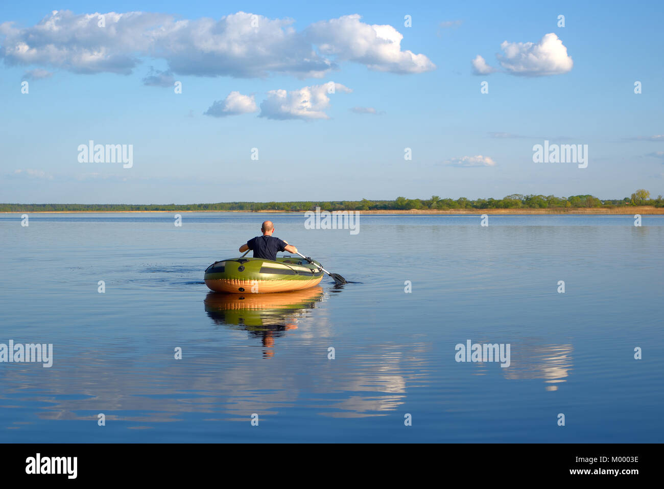 Man in an inflatable boat floats on the river, the view from the back