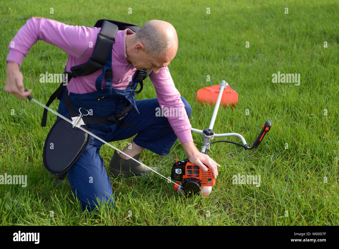 The man starts a weed trimmer on a lawn Stock Photo