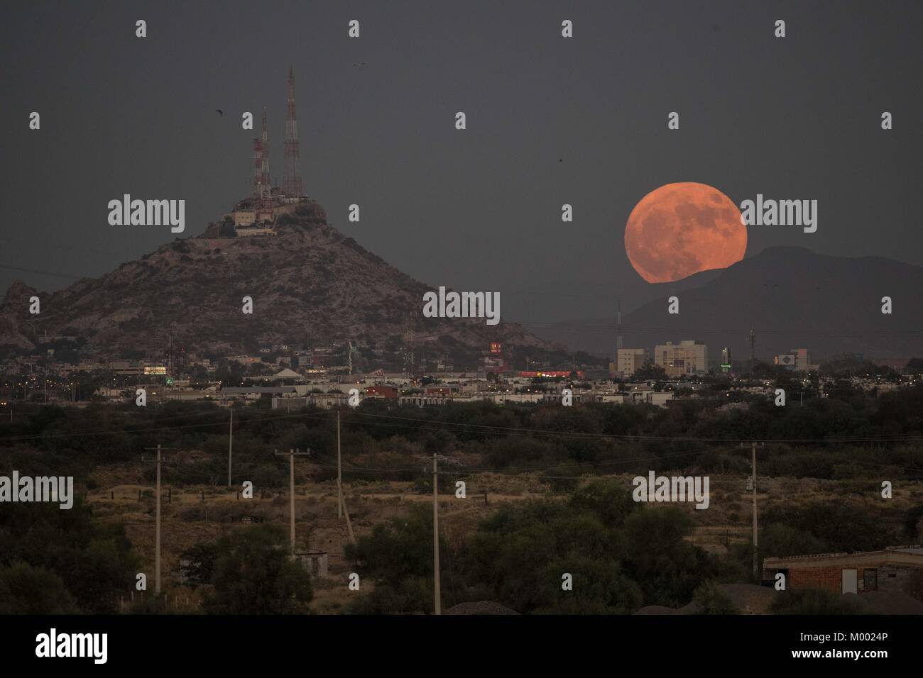 Espectacular vista de la Luna llena saliendo justo antes del anochecer, justo aun lado de el símbolo de Hermosillo, el cerro de la campana. Como cada  Stock Photo