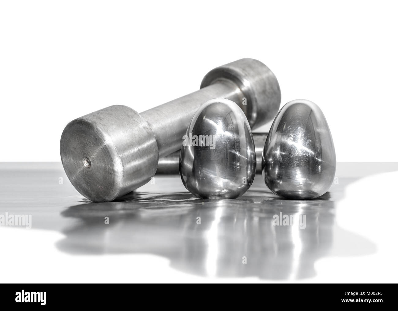 Metal dumbbells and steel eggs, the concept of sports training and the achievement of muscle strength Stock Photo