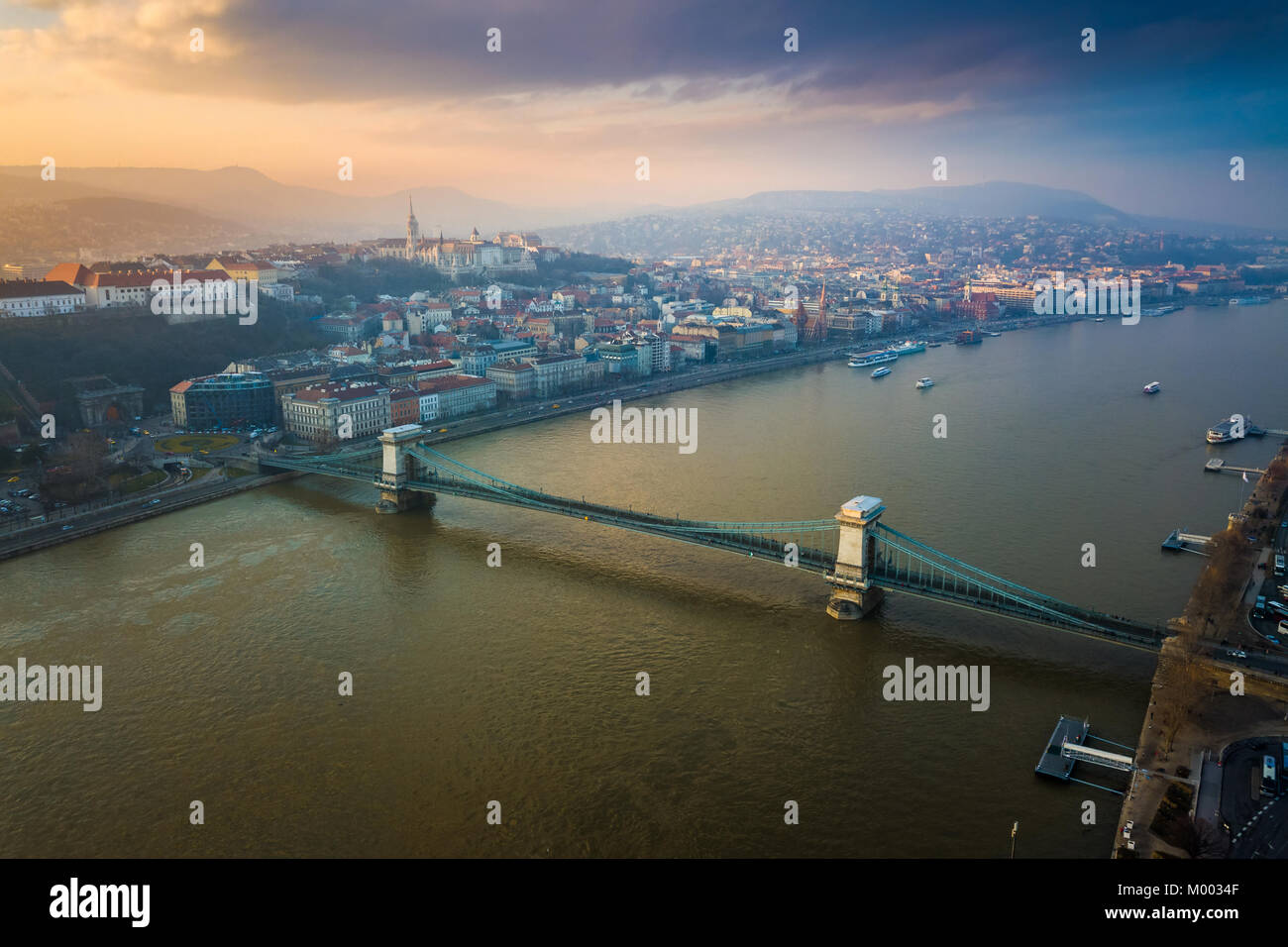 Budapest, Hungary - Aerial view of the famous Szechenyi Chain Bridge with Fisherman's Bastion and Matthias Church at background with beautiful sunset  Stock Photo