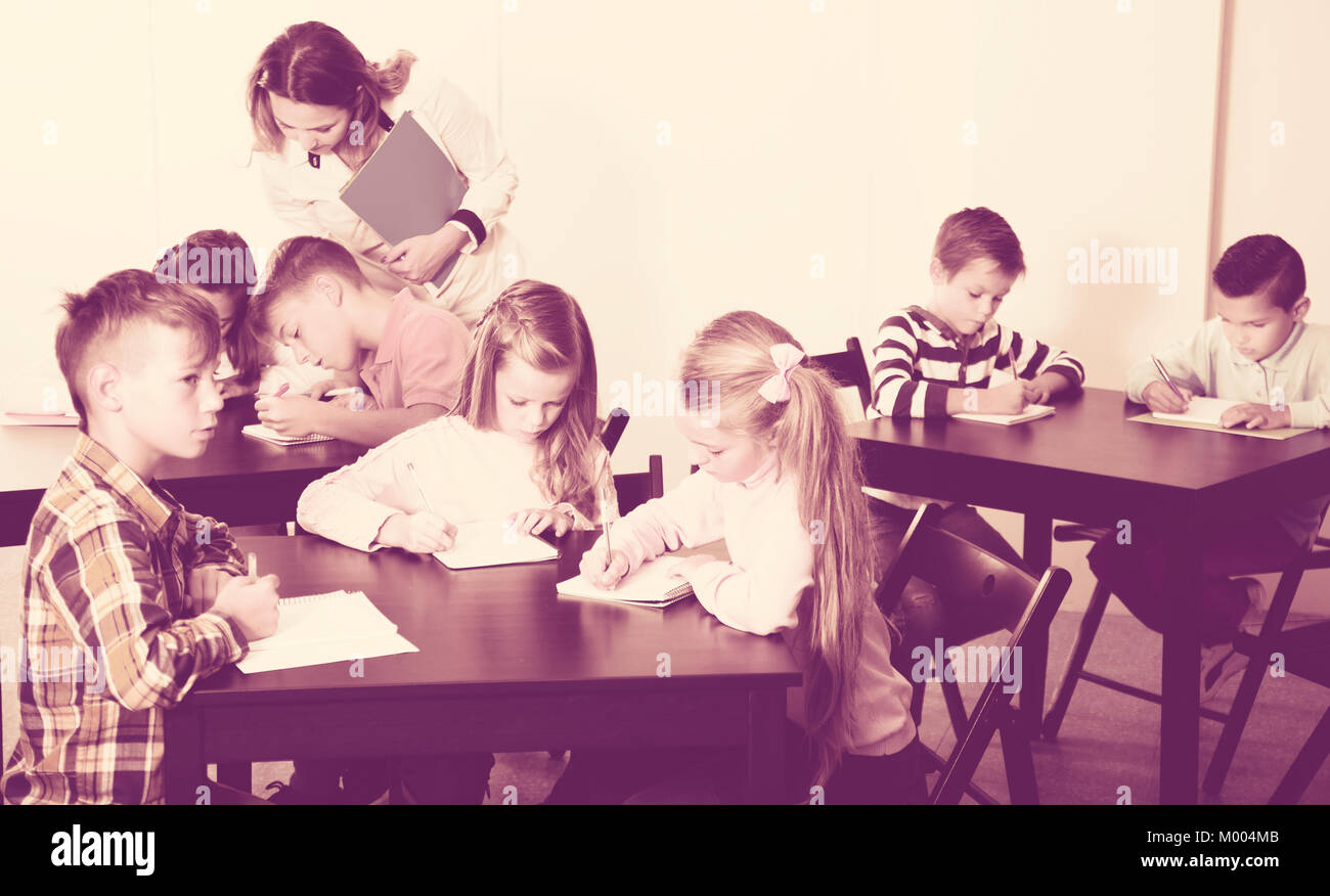Positive little boys and girls with teacher drawing in classroom Stock ...