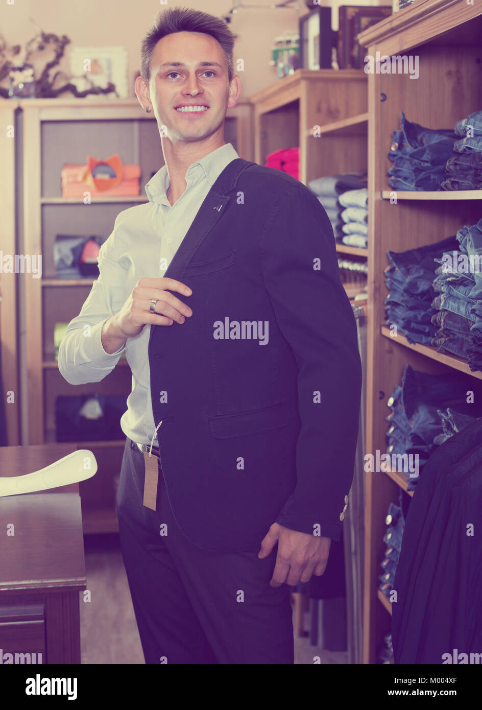 Smiling male choosing new suit in male clothing store Stock Photo - Alamy