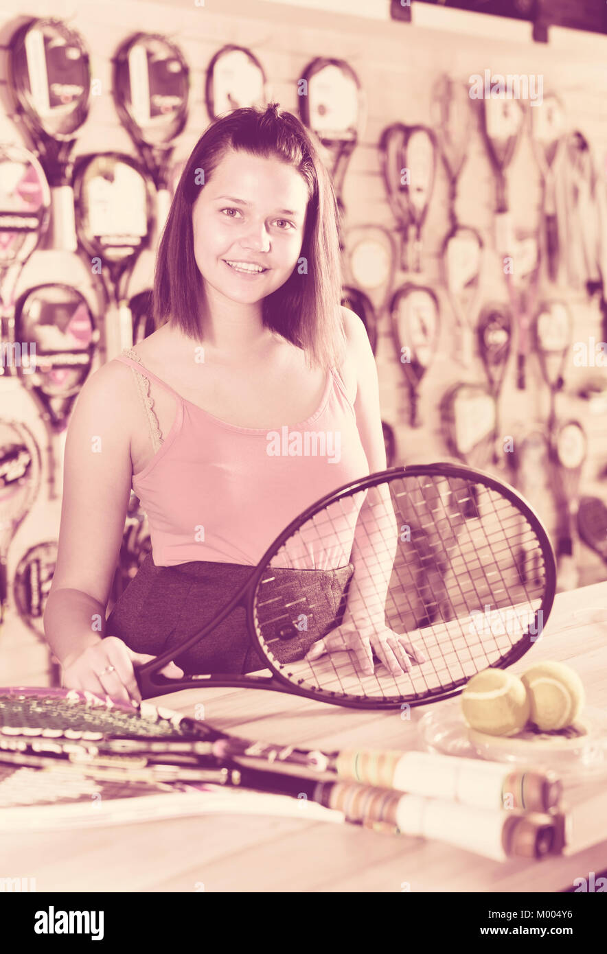 cheerful girl shows a tennis racket in the store Stock Photo - Alamy