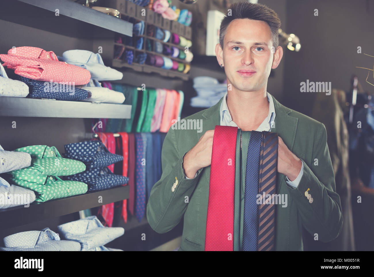 Smiling guy choosing new tie in male cloths store Stock Photo - Alamy