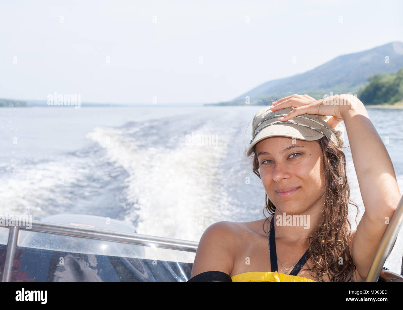 Young girl is riding on motorboat on the river in summer afternoon ...