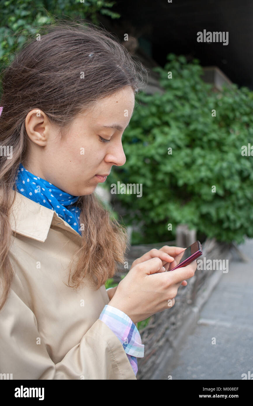 Young girl is looking in a smartphone that holds in his hands.  Stock Photo
