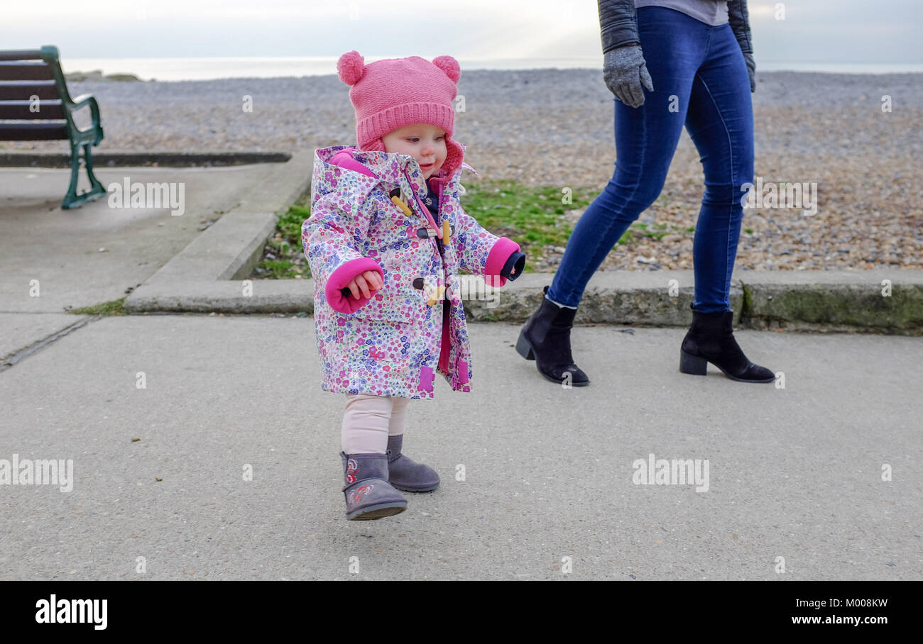One year old baby girl toddler walking on Rottingdean seafront Stock Photo