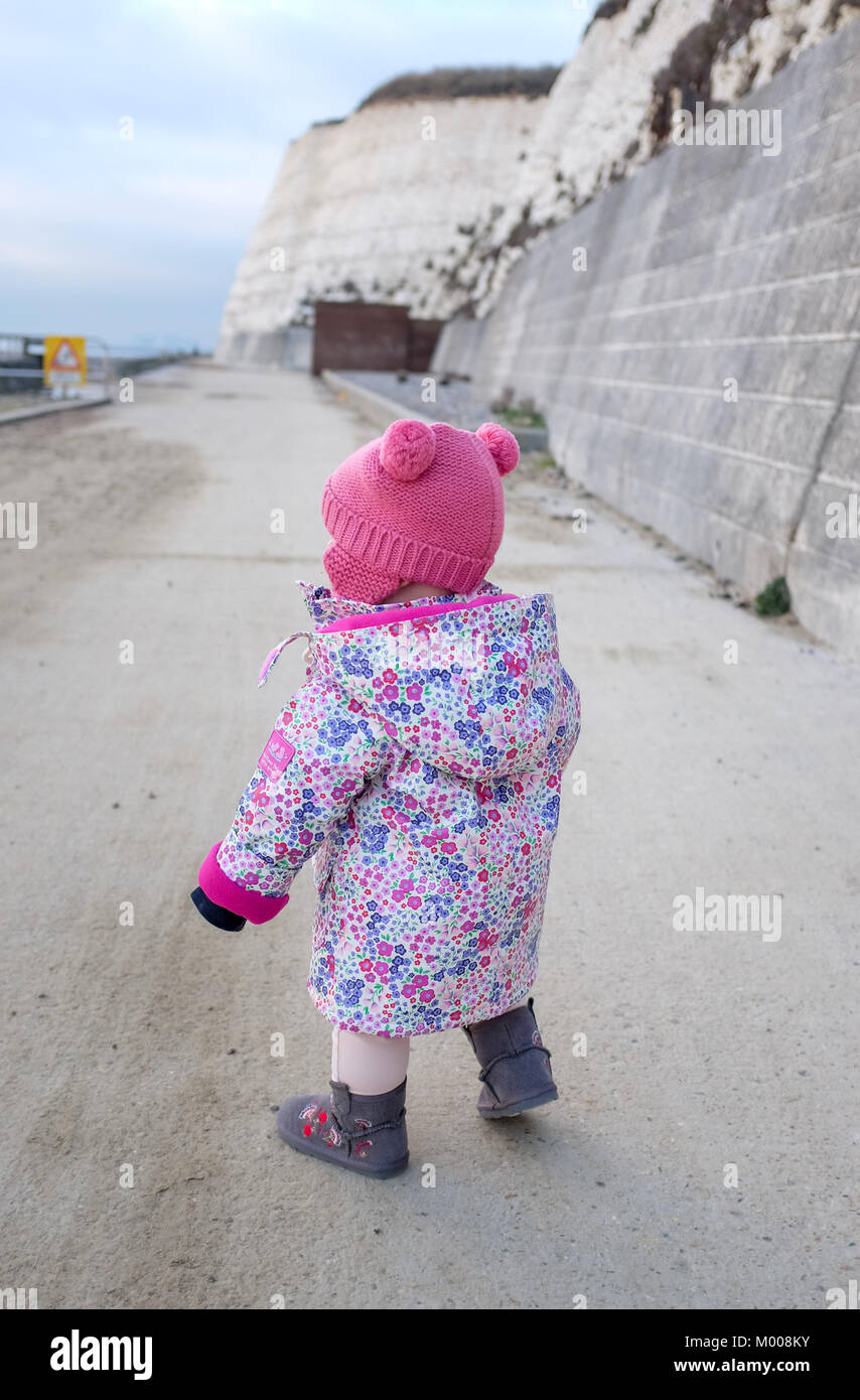 One year old baby girl toddler walking on Rottingdean seafront Stock Photo