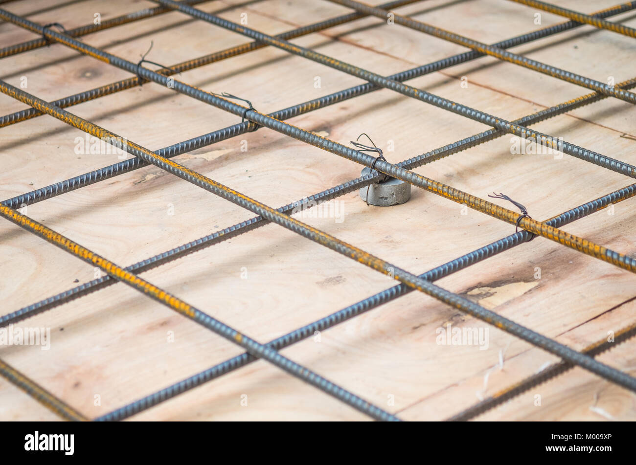Rebars steel wire mesh, which is supported by mortar cover box and wooden plate for precast concrete flooring on construction site, selective focus. Stock Photo