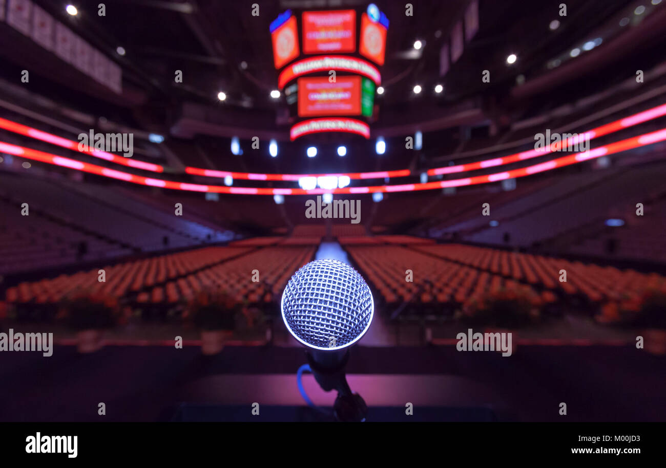 A solitary podium microphone on stage before an event at a large indor sports arena. Stock Photo