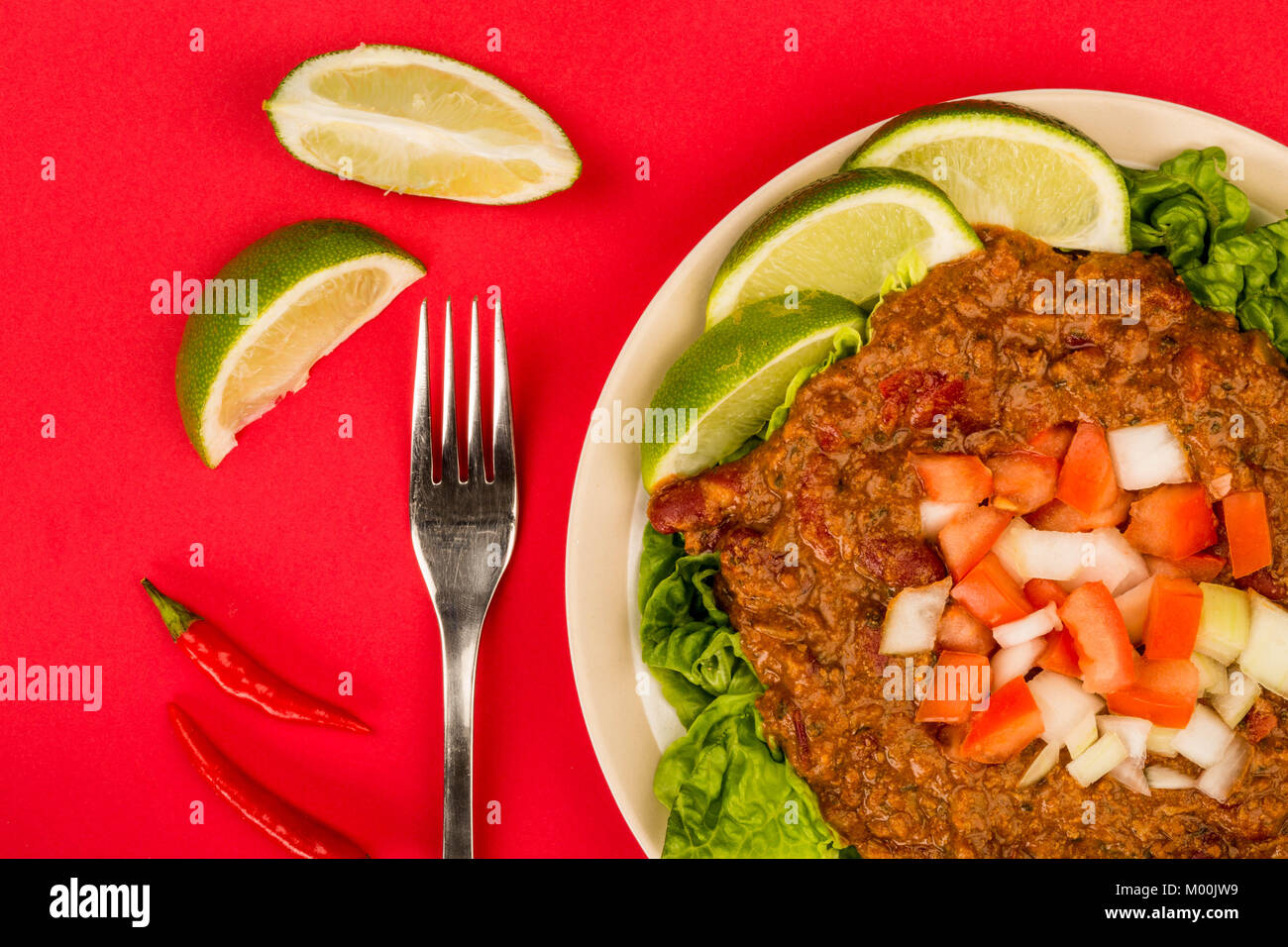 Spicy Mexican Style Beef Taco Meat and Salad With Fresh Limes Against A Red Background Stock Photo
