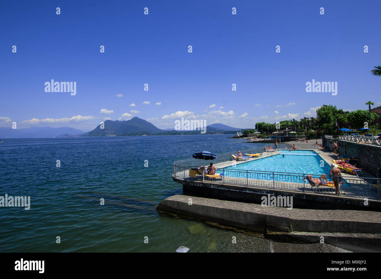 tourists during a summer holiday tan in a beautiful lake-side pool. Lake Maggiore, Italy Stock Photo