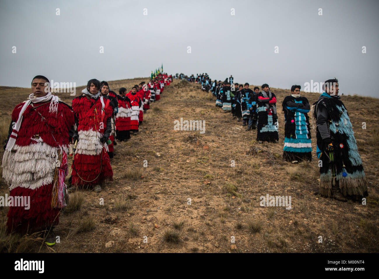 Cusco, Peru. 29th Dec, 2017. Members of the Quispicanchis nation of red and white accompanied by members of the Canchis nation of light blue and black await the sunrise after pilgrimage for 24 hours from the Hoyada de Sinancara to Mahuayani.Quyllur Rit'i or Star Snow Festival is a spiritual and religious festival held Annually at the Sinakara Valley in the Cusco Region of Peru. Groups of Quero indigenous people climb Ausangate Mountain, at 6362m, in search of the Snow Star Which is reputedly buried Within the mountain.According to the chroniclers, the Qoyllur Rit'i is the Christ that th Stock Photo