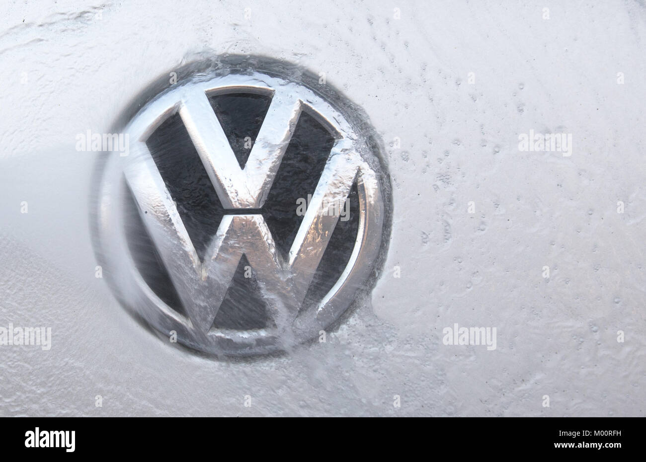 A vehicle's Volkswagen logo is being cleaned at a at a car wash