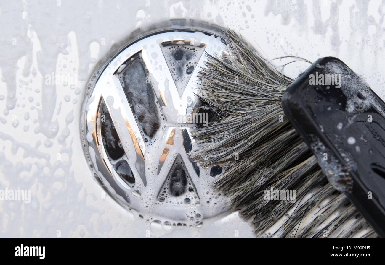 A vehicle's Volkswagen logo is being cleaned at a at a car wash