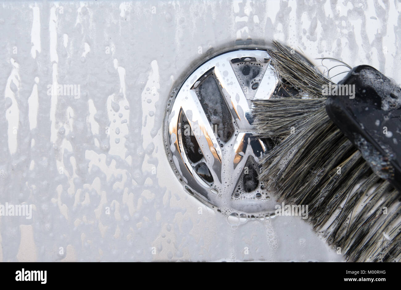 A vehicle's Volkswagen logo is being cleaned at a at a car wash