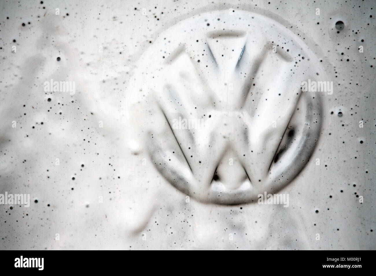 A vehicle's Volkswagen logo is being cleaned at a at a car wash
