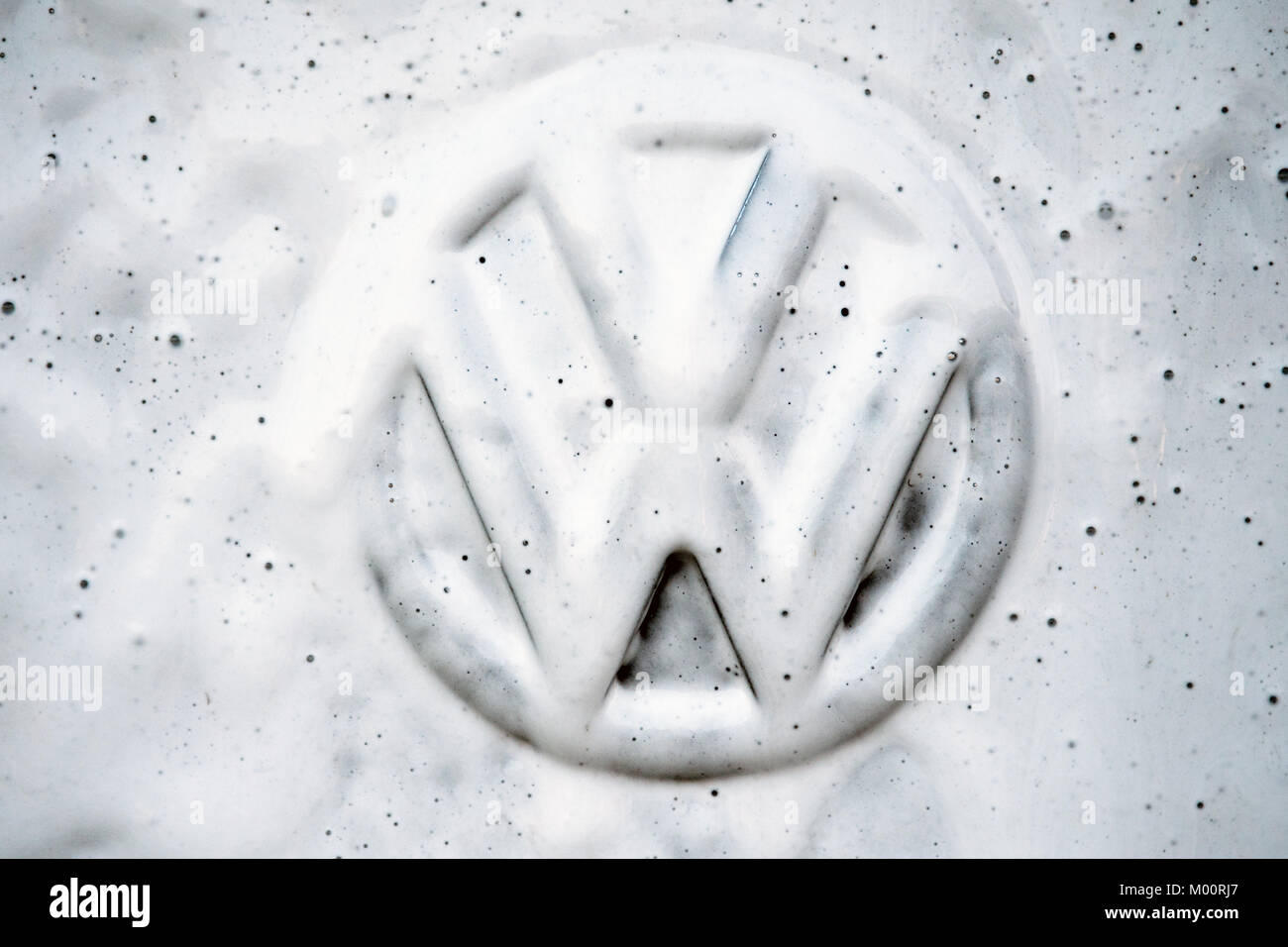 A vehicle's Volkswagen logo is being cleaned at a at a car wash