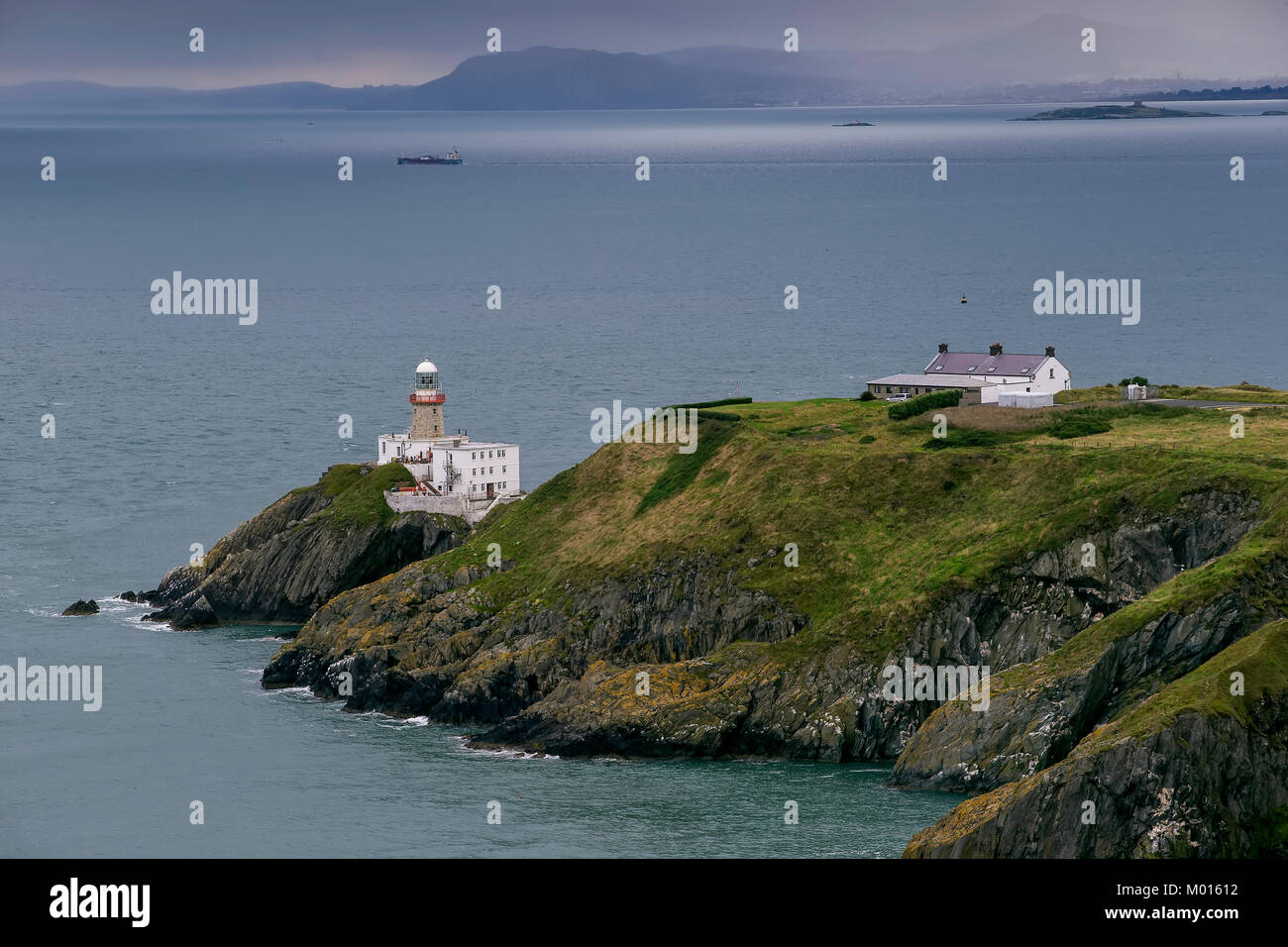 A photograph of the Bailey Lighthouse in Dublin bay with Dalkey Islands across the Bay and the Wicklow mountains in the Mist beyond that. Stock Photo