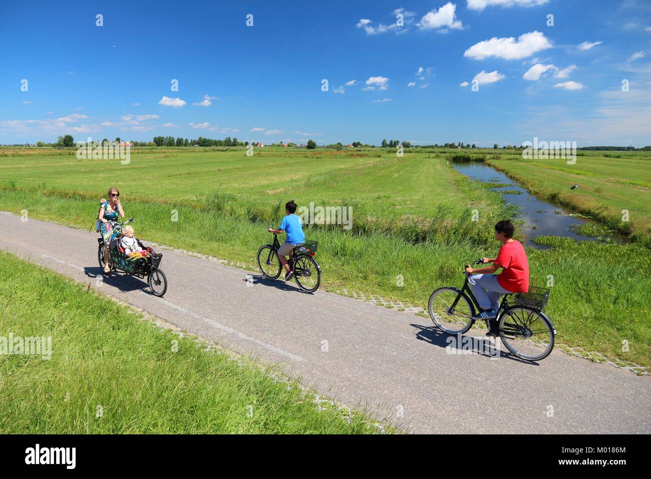 ZAANDAM, NETHERLANDS - JULY 9, 2017: Cyclists visit polder countryside of Kalverpolder in Zaandam. Netherlands has 35,000 km of cycleways physically s Stock Photo