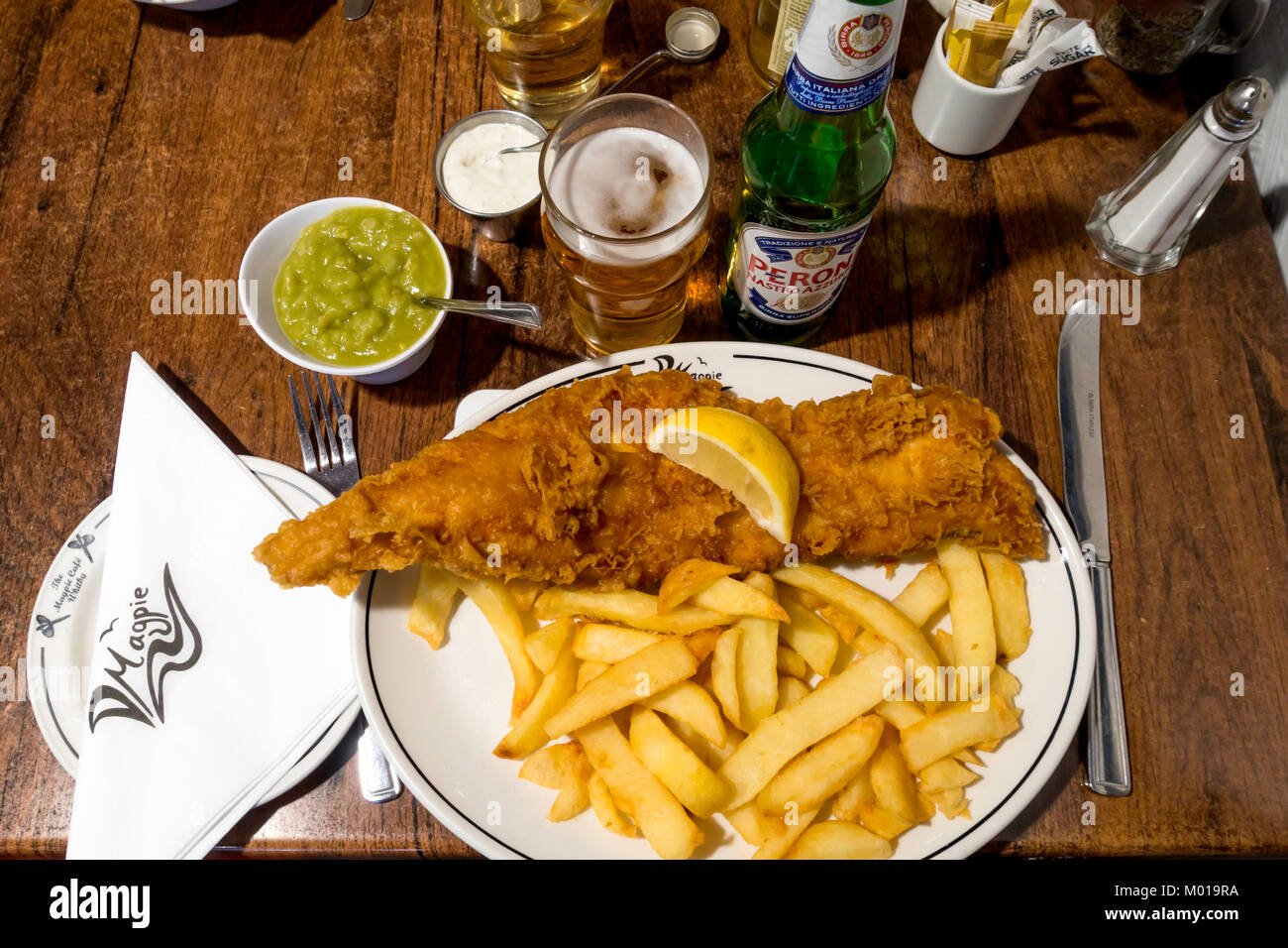 Excellent fish and chips at the famous Magpie Cafe in Whitby served with mushy peas tartare sauce and a drink of Peroni Italian lager Stock Photo