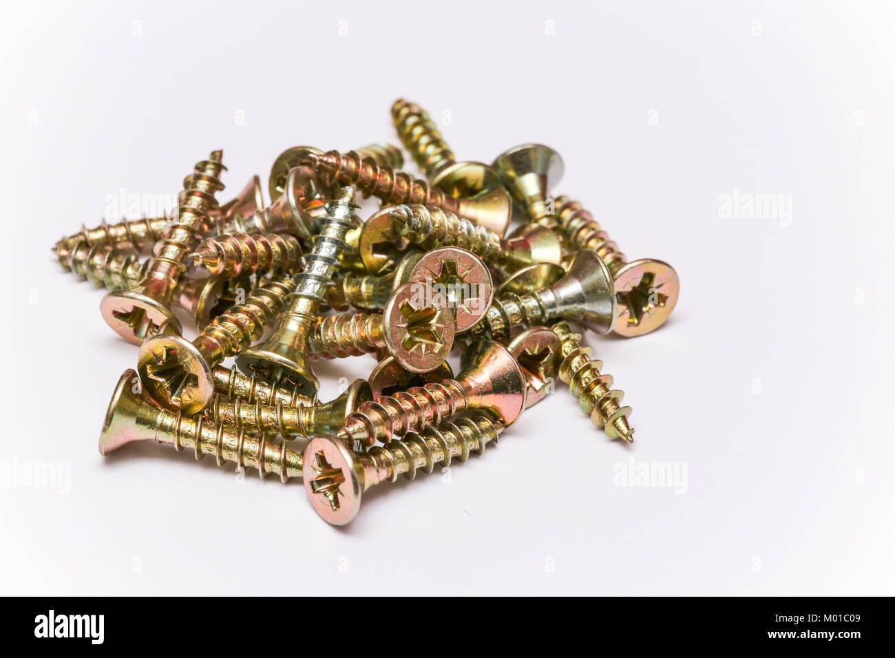 Bunch of yellow zinc coated philips flat head cross screws - fasteners on a white background Stock Photo