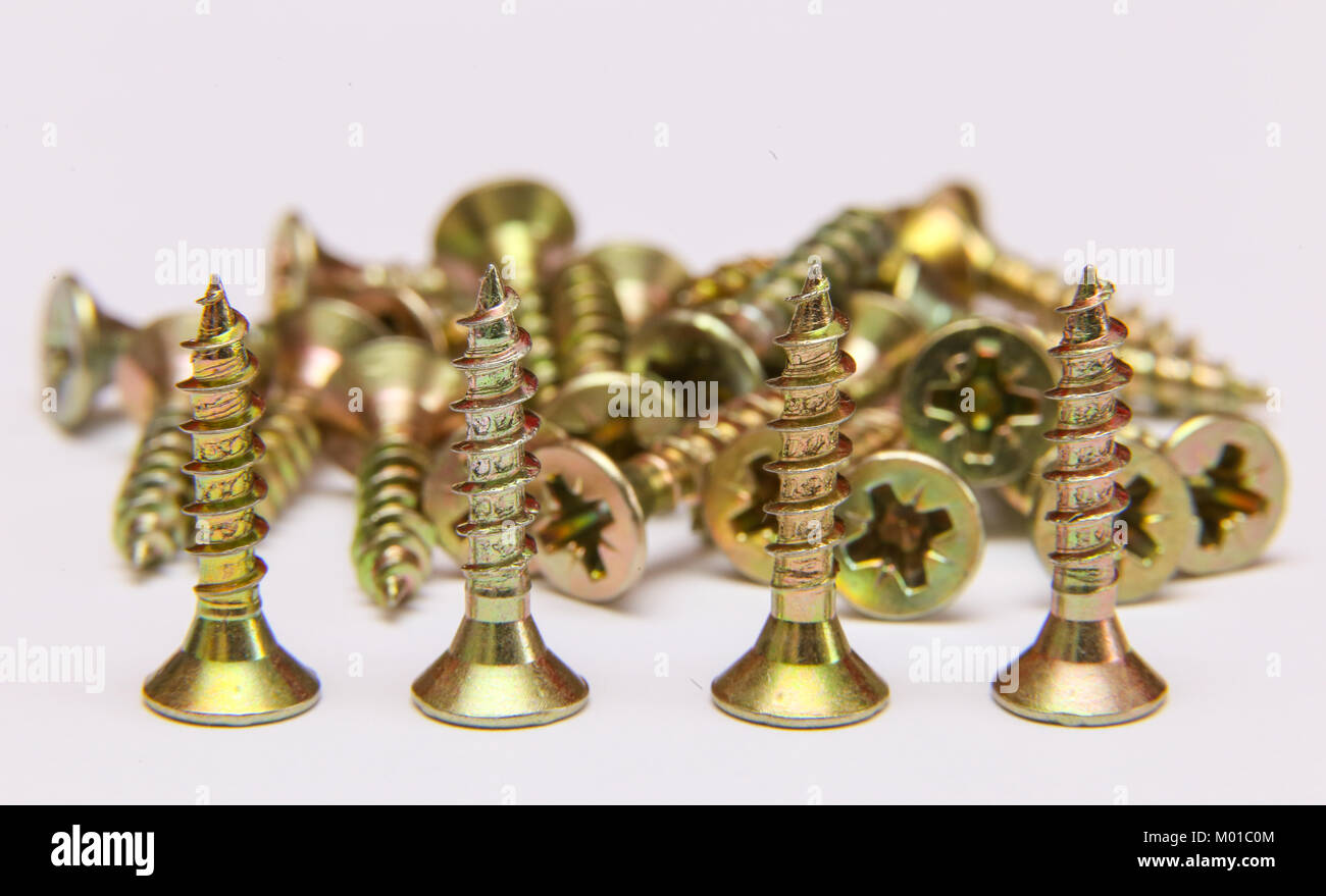 Bunch of yellow zinc coated philips flat head cross screws - fasteners on a white background Stock Photo