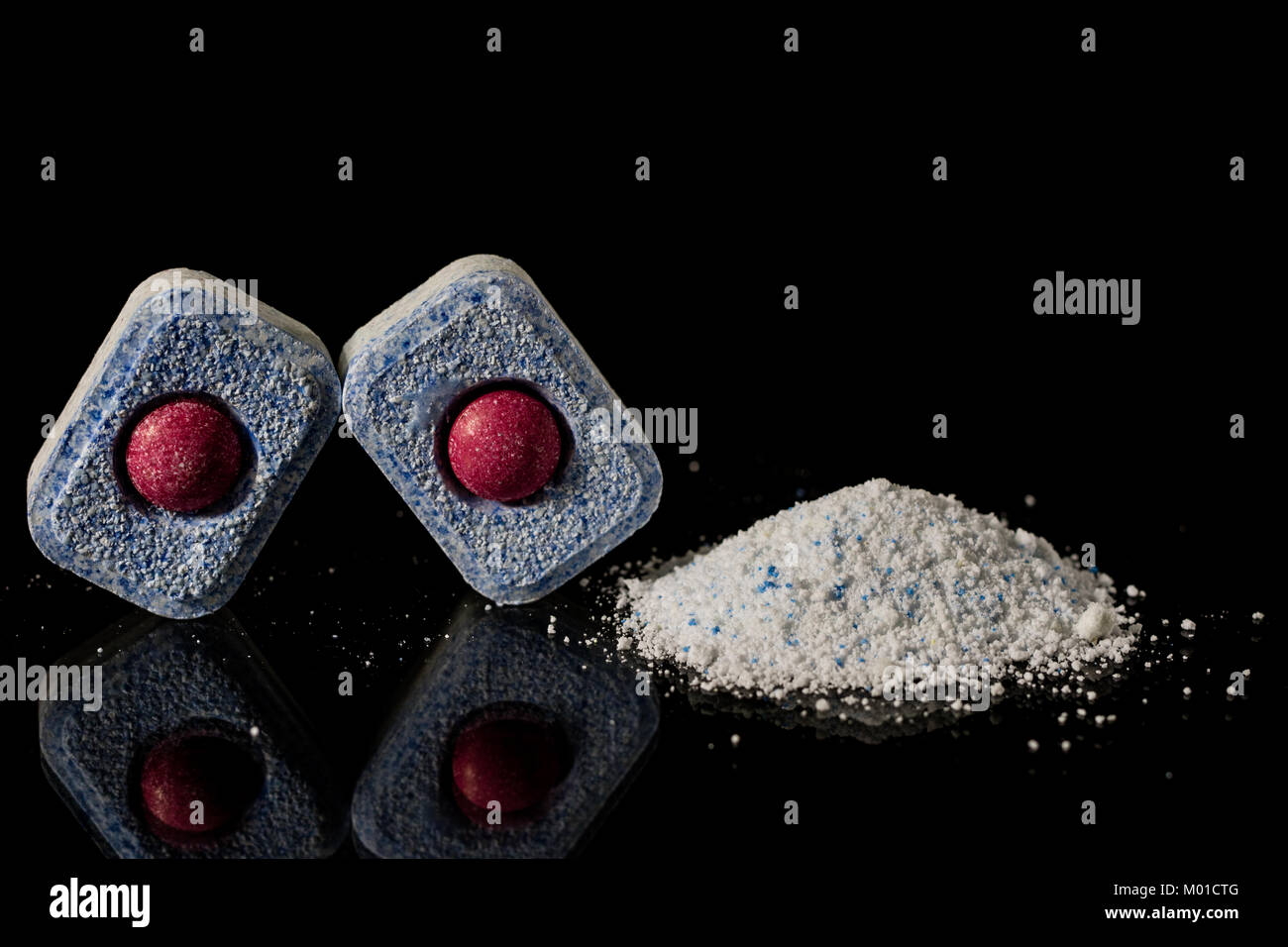 Tablet and powder for the dishwasher. Comparison of two detergents. Black background Stock Photo