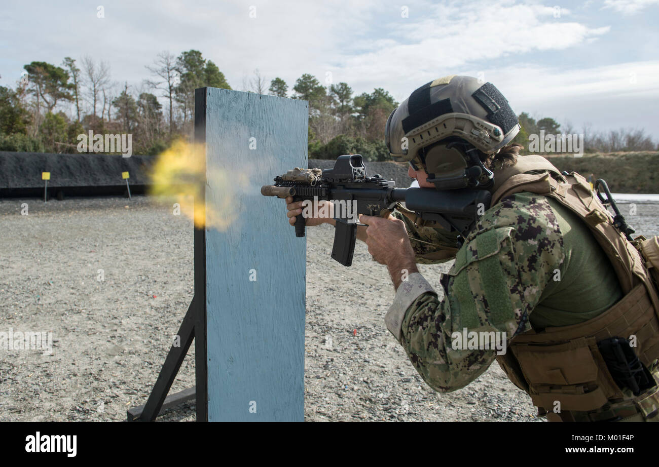 A U.S. Navy explosive ordnance disposal technician assigned to Explosive Ordnance Disposal Mobile Unit (EODMU) 12 fires an M4 rifle from behind cover during a live-fire training exercise in Moyock, North Carolina, Jan. 11, 2018. Stock Photo