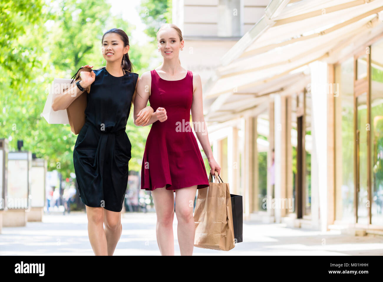 Two fashionable young women walking in the city during shopping Stock ...