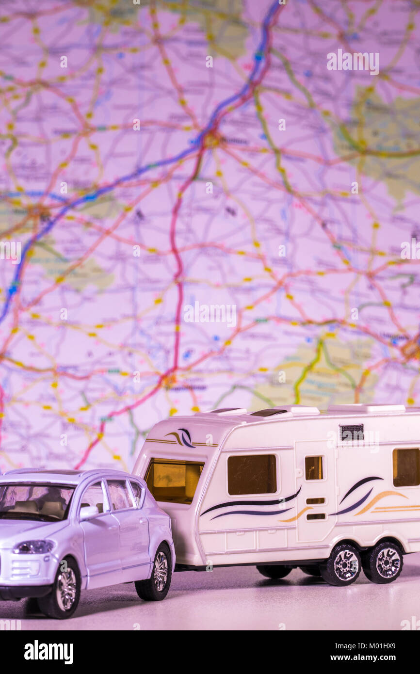 Model caravan and car with a defocused map / atlas in the background. Concept of any aspect of camping / touring / freedom of the open road, etc. Stock Photo