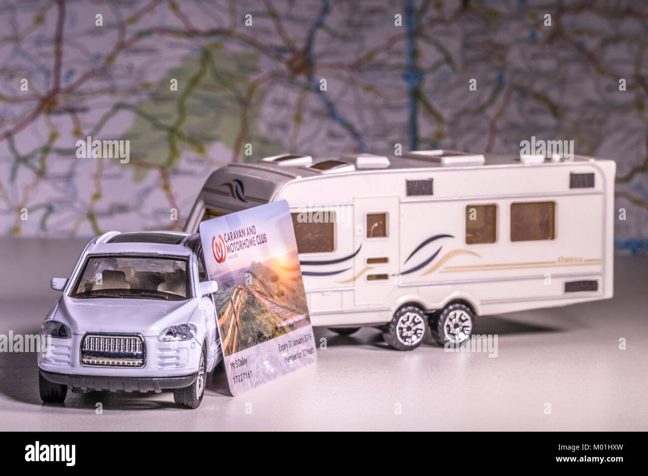 Model caravan and car with UK 'Caravan and Motorhome Club' membership card and defocused map / atlas. Concept of touring using a campsite network. Stock Photo