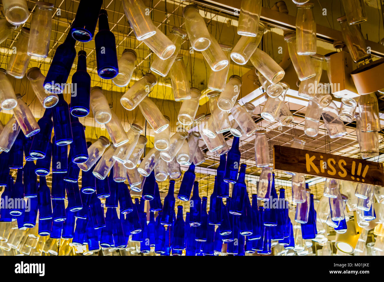 Colorful bottles hanging from ceiling, from below. Ceiling with blue