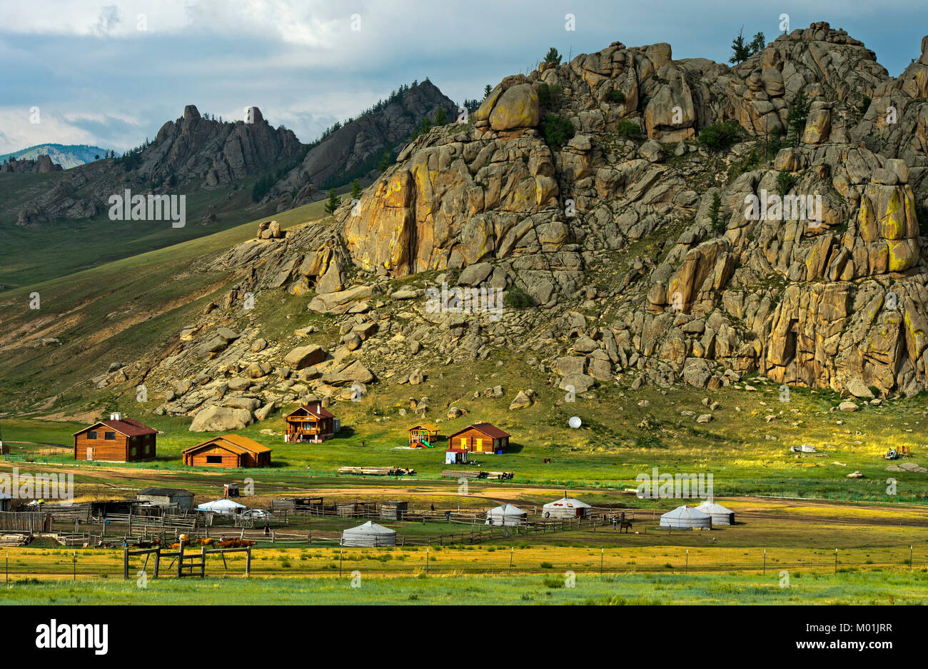 Hamlet with yurts and blockhouses in front of a rocky peak in the Mongolian steppe, Gorkhi-Terelj National Park, Mongolia Stock Photo