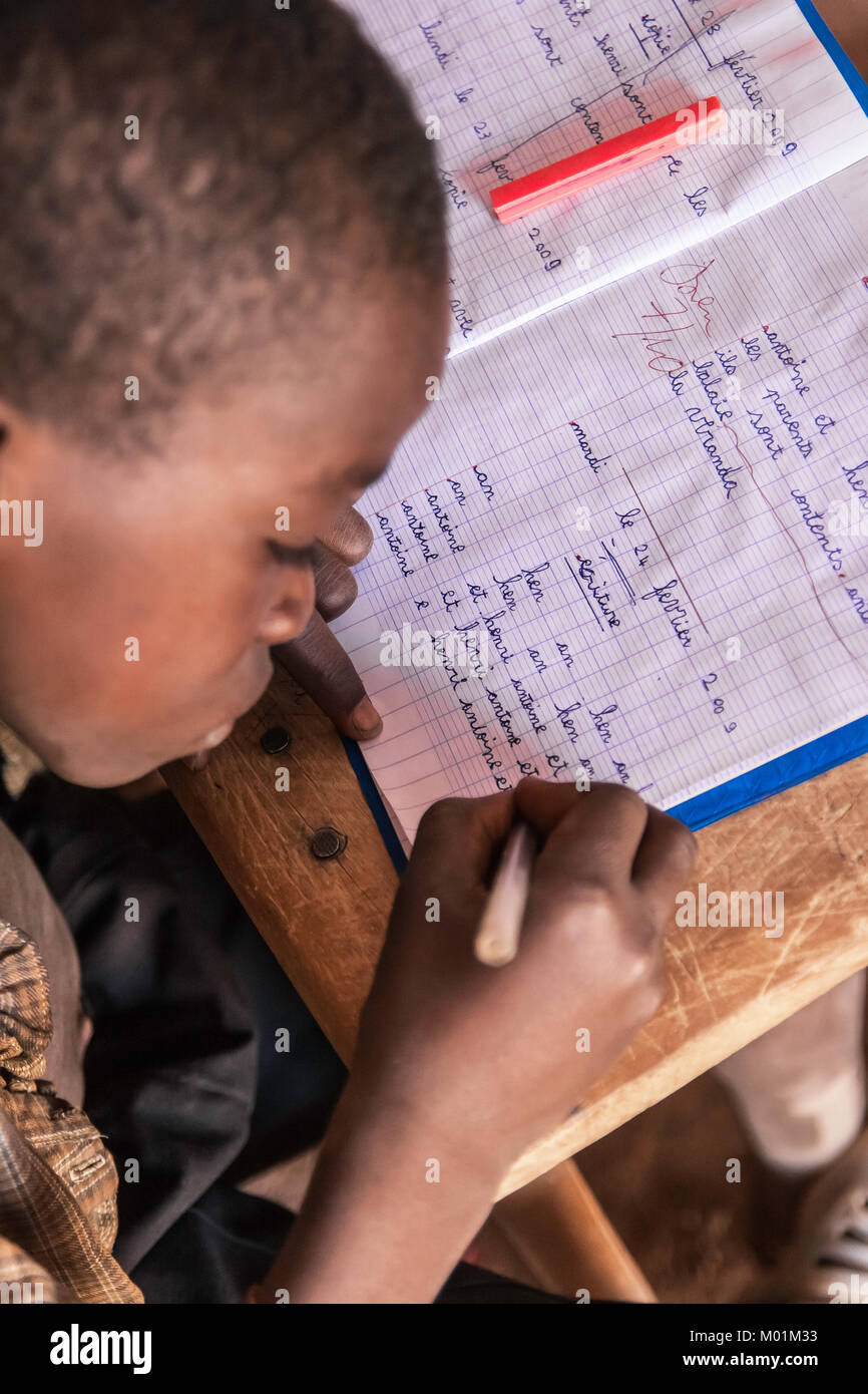 An african schoolkid writing in his workbook during an ongoing lesson, Ouagdougou, Burkina Faso. Stock Photo