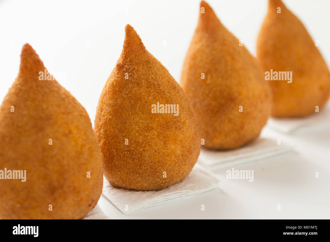 Deep fried chicken finger food known as Coxinha in Brazil. Brazilians eat as fast food alternative or at parties. Three snacks on a row over white tab Stock Photo