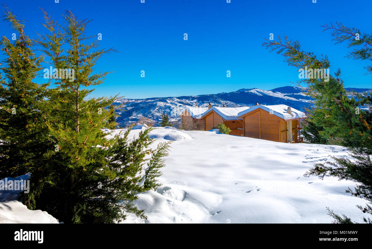 Winter landscape with snow, wooden houses and clear blue sky, Trikala Korinthias, Greece. Stock Photo