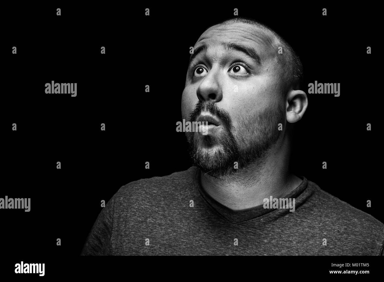 A high contrast black and white emotional and surprised portrait of a hispanic man. Stock Photo