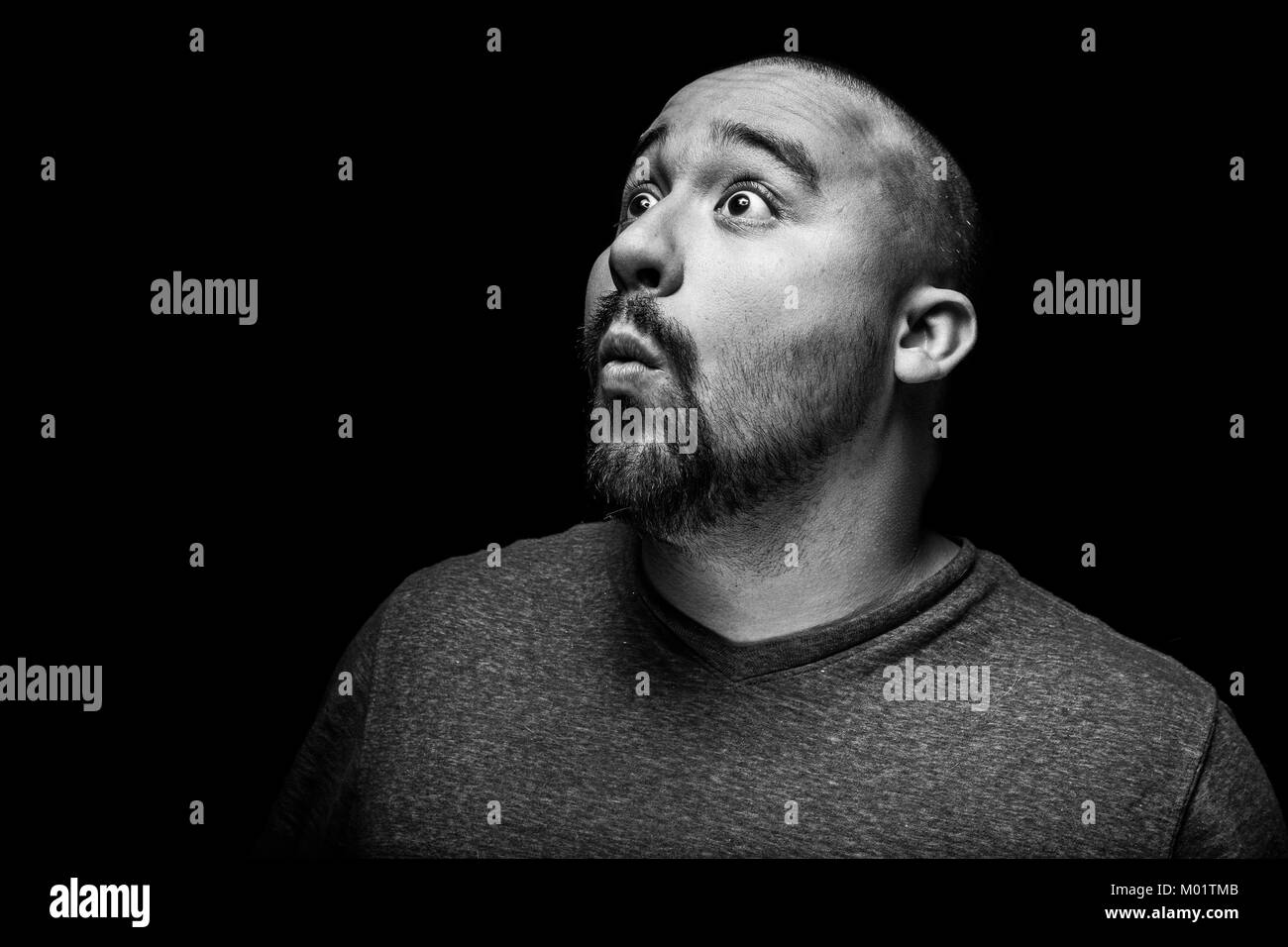 A high contrast black and white emotional and surprised portrait of a hispanic man. Stock Photo