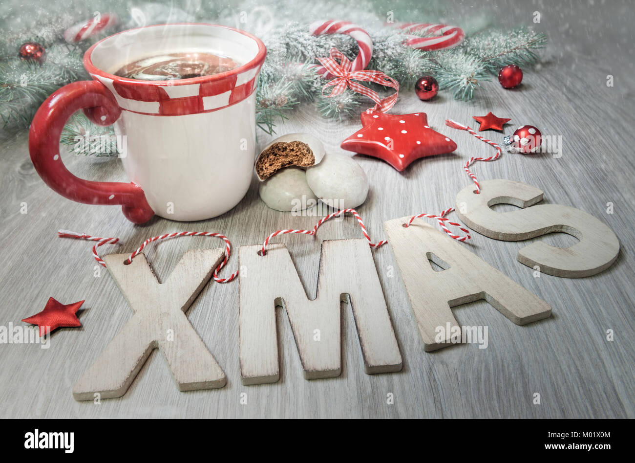 Wooden letters "Xmas", cup of steaming tea and winter decorations in red and dark green. Merry Christmas! Stock Photo