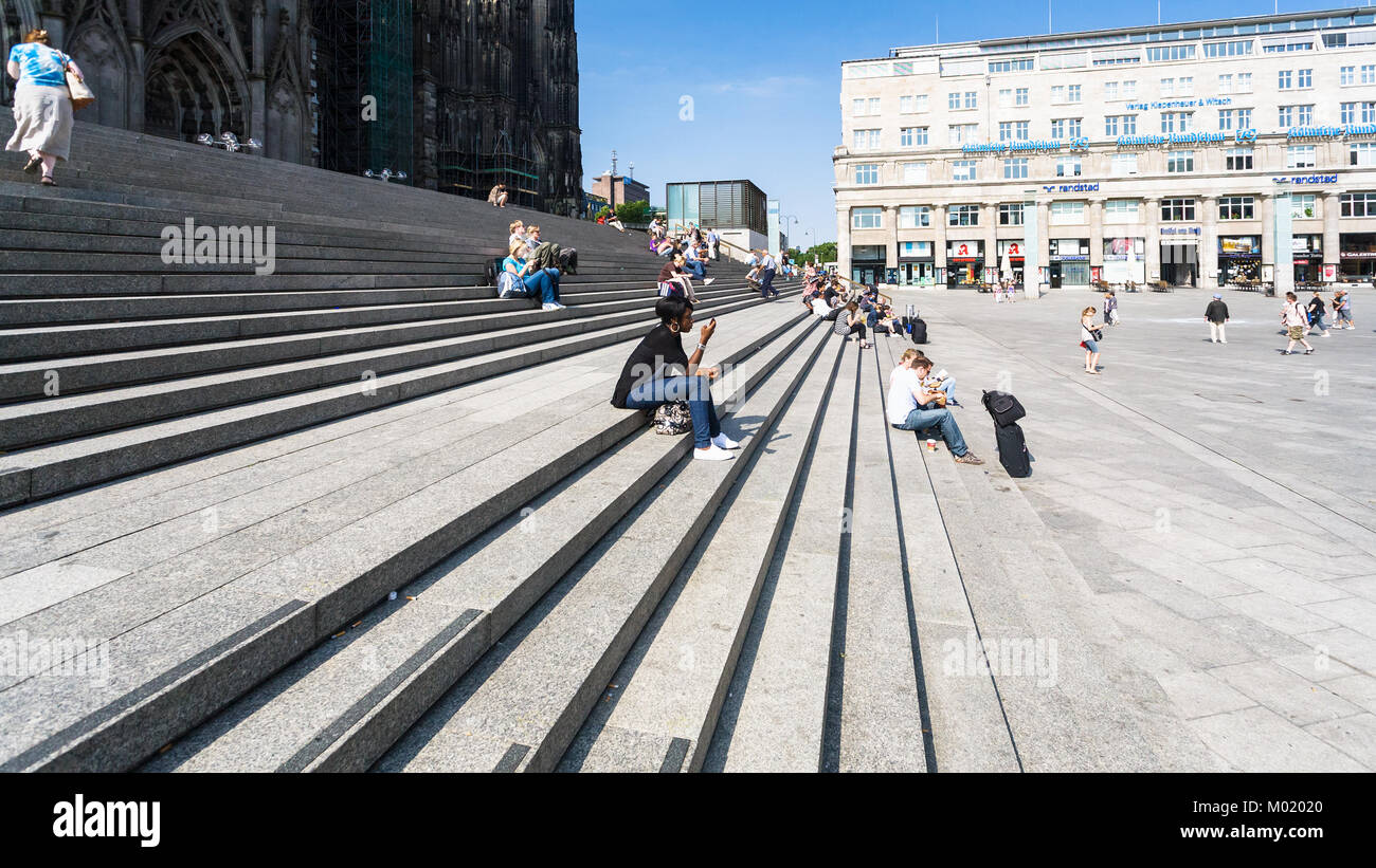 COLOGNE, GERMANY - JUNE 27, 2010: tourists on steps in front of Cologne Cathedral on Bahnhofsvorplatz. The Cathedral is Germany's most visited landmar Stock Photo