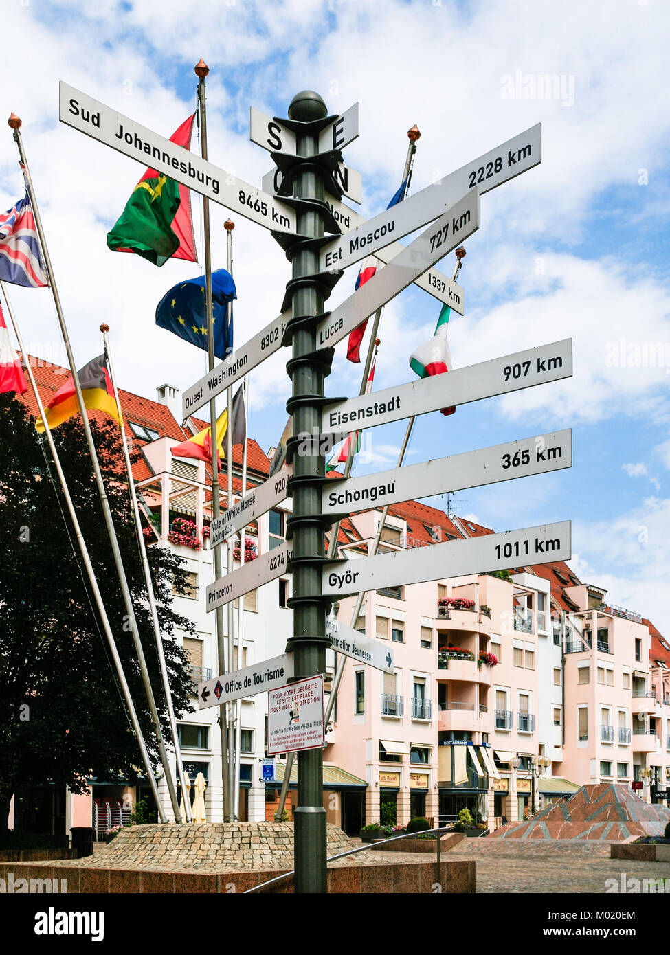 COLMAR, FRANCE - JULY 11, 2010: geographic marker with travel distance to cities and european flags on square Place de la Mairie in Colmar city. Colma Stock Photo