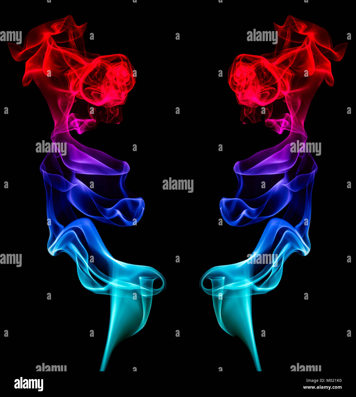 Two artistic mirror-image columns of red blue and green smoke providing a central black space for copy Stock Photo