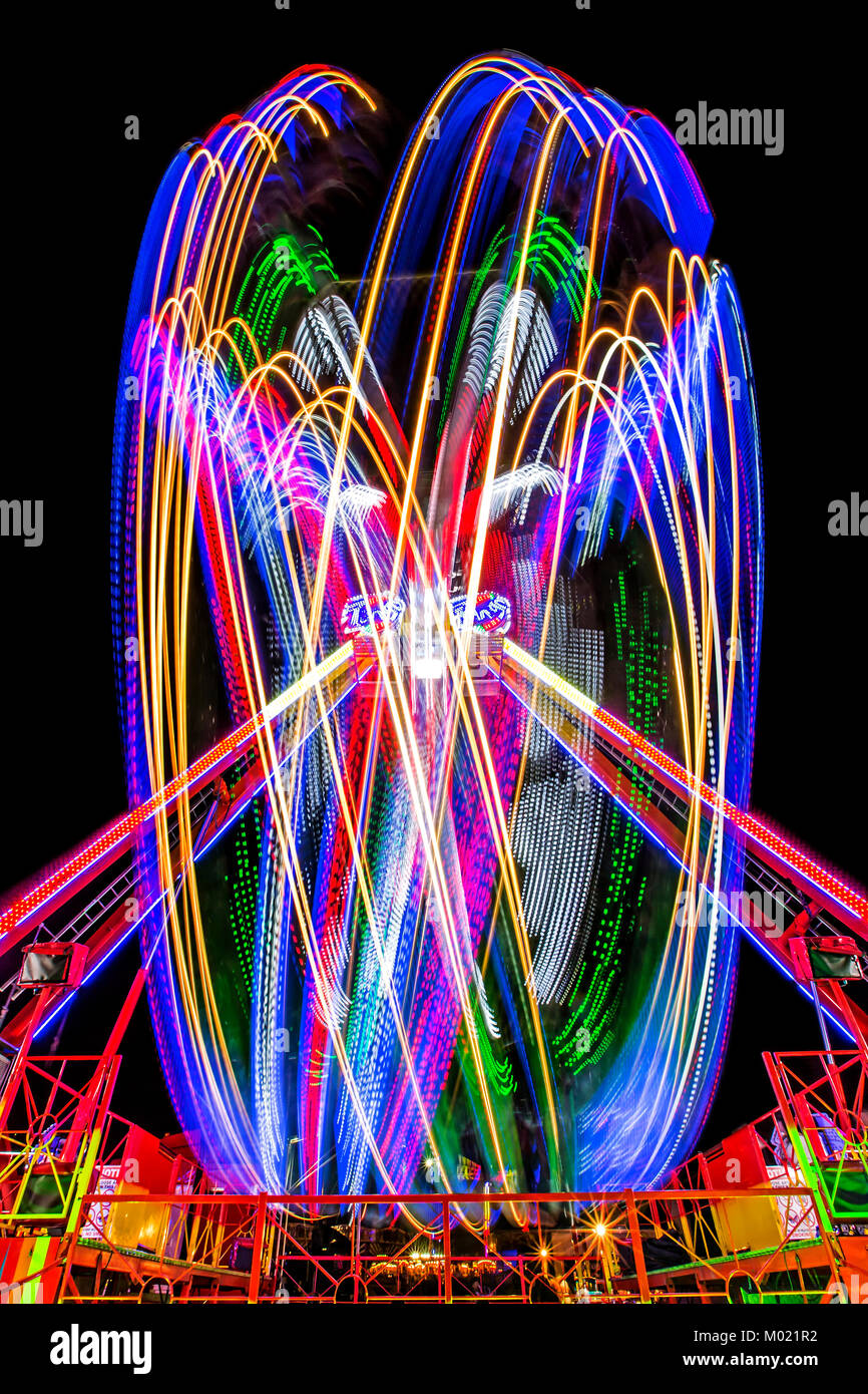 An artistic colourful night-time image of a scary ride in the fairground of the Great Dorset Steam Fair UK. Stock Photo